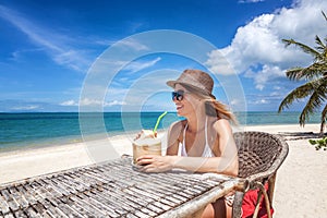 Happy blonde woman in hat and sunglasses on the tropical beach s