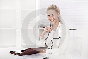 Happy blonde woman sitting at desk.