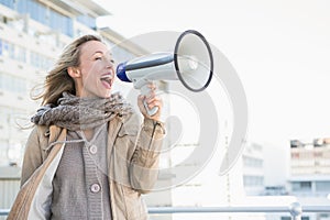 Happy blonde woman speaking on megaphone