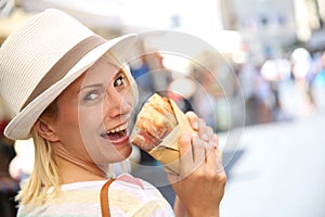 Happy blonde woman tasting Focaccia sandwich
