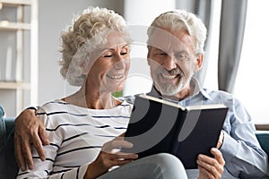 Happy bonding elderly senior retired family couple reading paper book.