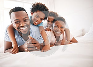 Happy, bonding and portrait of a black family on a bed for playing, quality time and comfort. Smile, love and African