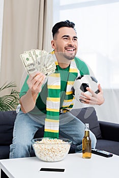 happy bookmaker holding dollars and soccer