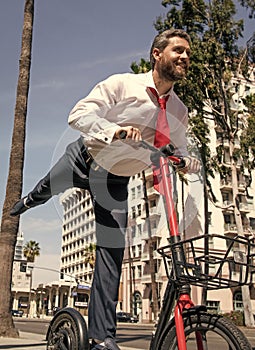 Happy boss in formalwear ride city scooter along sidewalk, scooting