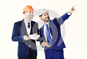 Happy boss pointing something to employee. Businessman and building surveyor with smiling and cheerful faces. Site