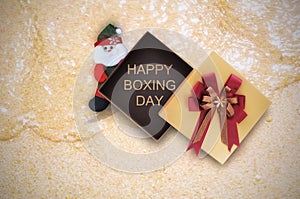 Happy boxing day word in gift box with Santa Claus on tropical beach background