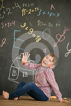 Happy boy on the background of a school board showing five fingers