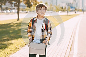 A happy boy with a backpack and tablets returns home from school. The student is happy about the end of classes. Training,