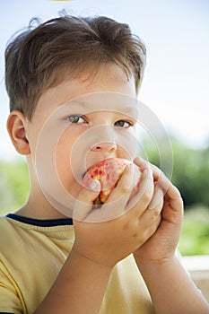 Happy boy biting the apple, A child with a fruit. Kid eating fresh pear