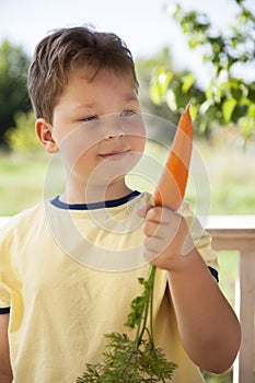 Happy boy biting the carrot, A child with a vegetable. Kid eating fresh carrots