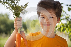 Happy boy biting the carrot, A child with a vegetable. Kid eating fresh carrots