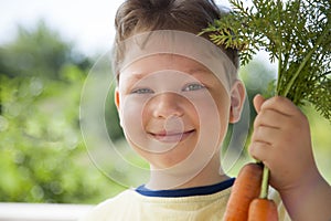 Happy boy biting the carrot, A child with a vegetable. Kid eating fresh carrots