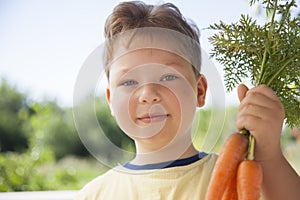 Happy boy biting the carrot, A child with a vegetable. Kid eating fresh carrots