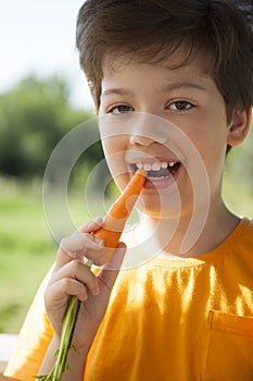 Happy boy biting the carrot, A child with a vegetable. Kid eating fresh carrots