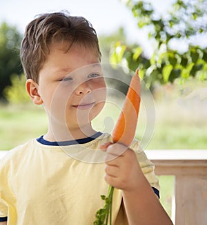 Happy boy biting the carrot, A child with a vegetable. Kid eating fresh carrots