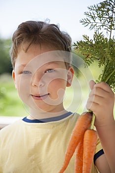 Happy boy biting the carrot, A child with a vegetable. Kid eating fresh carrots