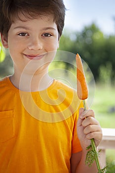 Happy boy biting the carrot, A child with a vegetable. Kid eating fresh carrots