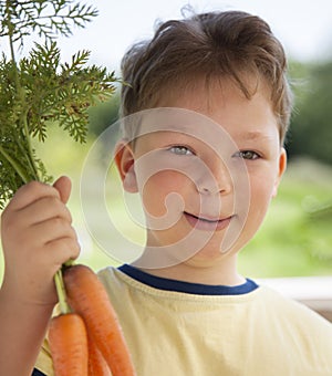 Happy boy biting the carrot, A child with a vegetable. Kid eating fresh carrots