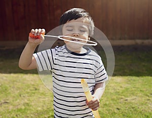 Happy boy blowing soap bubbles in the garden,Cute 4 years old kid blowing bubble wand with a funny face,Cute kid playing in the ga