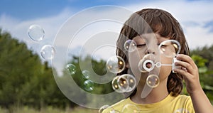 Happy Boy blowing a soap bubbles toy in garden sunny summer day