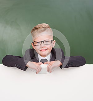 Happy boy in a business suit behind blank billboard