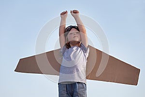 Happy boy with cardboard boxes of wings against sky dream of fly