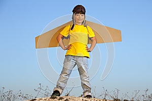 Happy boy with cardboard boxes of wings against sky dream of fly