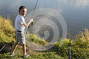 Happy boy caught a fish. Boy fishing on a lake. Child holding fishing rod. Little fisherman