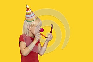 Happy boy celebrating his birthday. Party hat, red clown nose and blowing whistle. Copy space