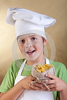 Happy boy with chef hat holding raw pasta in small sack