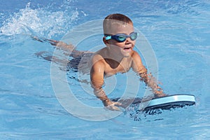 Happy boy child in swimming goggles swim in pool. Safe pool training, summer holiday, family vacation, water sport