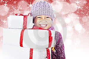 Happy boy with christmas boxes on defocused light