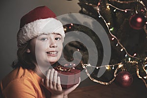 Happy boy with christmas gift near Christmas tree