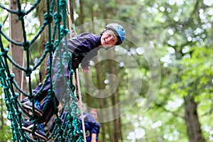 Happy boy climbing in adventure park