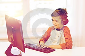 Happy boy with computer and headphones at home