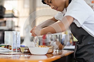 Happy boy cracking an egg for baking a cake in kitchen.