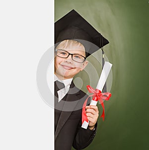 Happy boy with diploma in graduation hat looks out from behind a banner