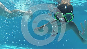 Happy Boy dive in swimming pool and looking at the camera, underwater shoot, sun rays