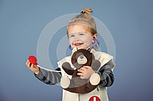 Happy boy in doctor uniform examine toy pet with stethoscope