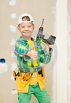 Happy boy with a drill and tool belt showing thumbs up