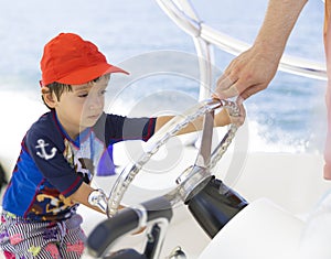 Happy boy driving a boat, enjoying summer