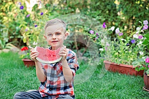 Happy boy eating watermelon in the garden. Kids eat fruit outdoors. Healthy snack for children