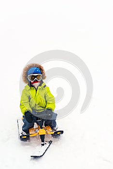 Happy boy enjoying sleigh ride. Snowy park in winter. Outdoors fun for family Christmas vacation. Winter holidays