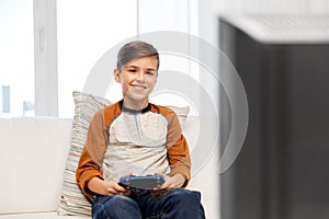 Happy boy with gamepad playing video game at home