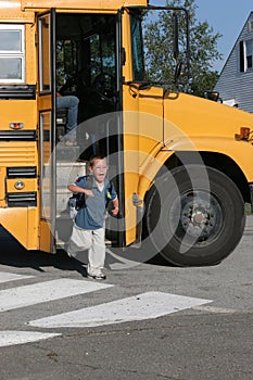 Happy boy getting off the school bus