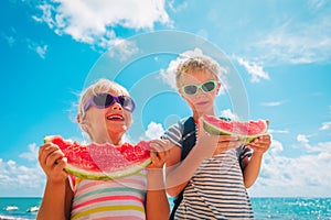Happy boy and girl eat watermelon at beach, healthy lifestyle