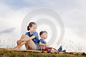 Happy boy and girl with guitar having fun outdoor, Portrait of adorable brother and sister playing outdoors. Asian kids singing