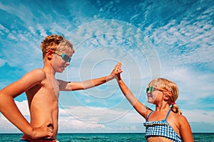 Happy boy and girl play on beach, kids have fun at sea