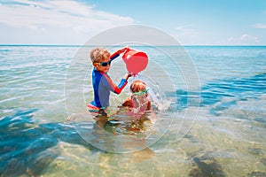 Happy boy and girl play on beach, kids splash water and have fun