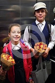 Happy boy and girl in school uniform with flowers